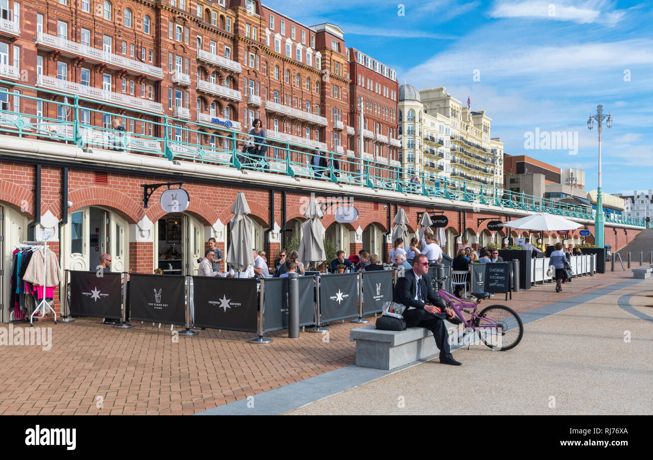 People, cafes and shops along the seafront at the Kingsway Arches in Brighton, East Sussex, England, UK. Stock Photo