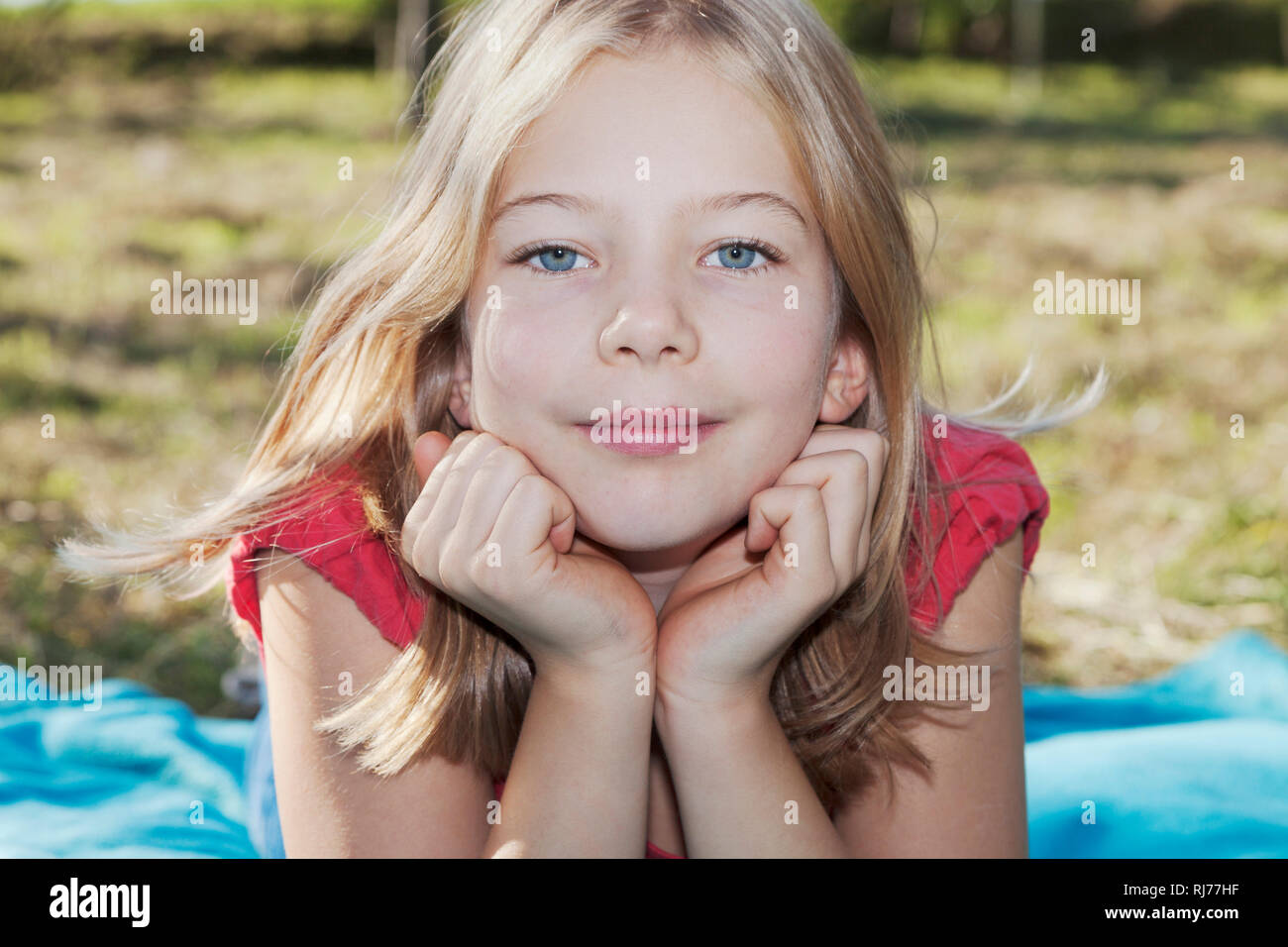Portrait eines neunjähriges Mädchen auf einer Wiese, Kopf in die Hände gestützt Stock Photo