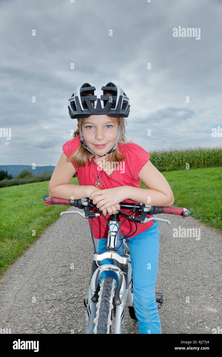 Neunjähriges Mädchen mit Helm auf einem Fahrrad Stock Photo