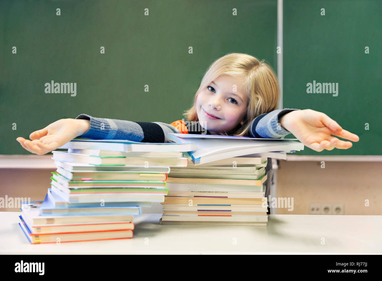 Schülerin, 9 Jahre alt, vor zwei Stapeln Bücher vor einer Tafel Stock Photo