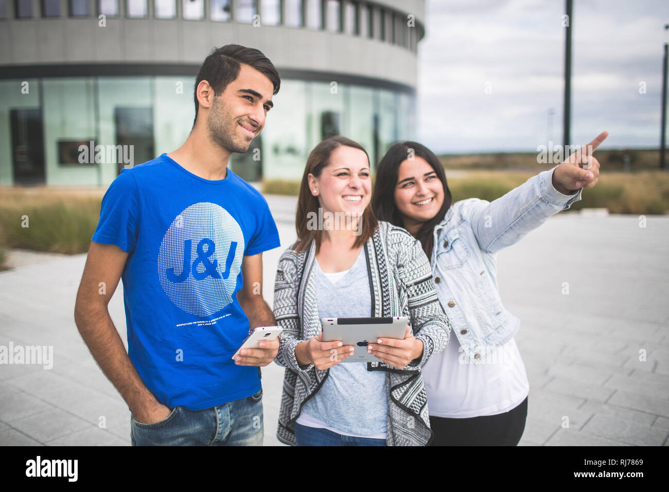 Drei Jugendliche mit Tablet und Smartphone unterwegs Stock Photo