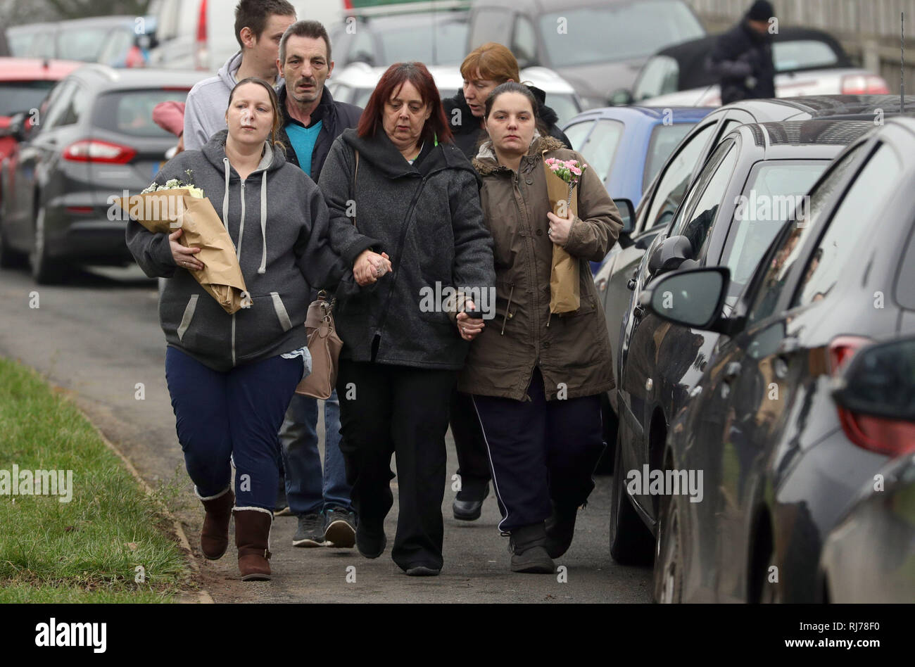 Unidentified family and wellwishers arrive to lay floral tributes at the scene of a house fire in Sycamore Lane, Stafford, which claimed the lives of four children. Stock Photo