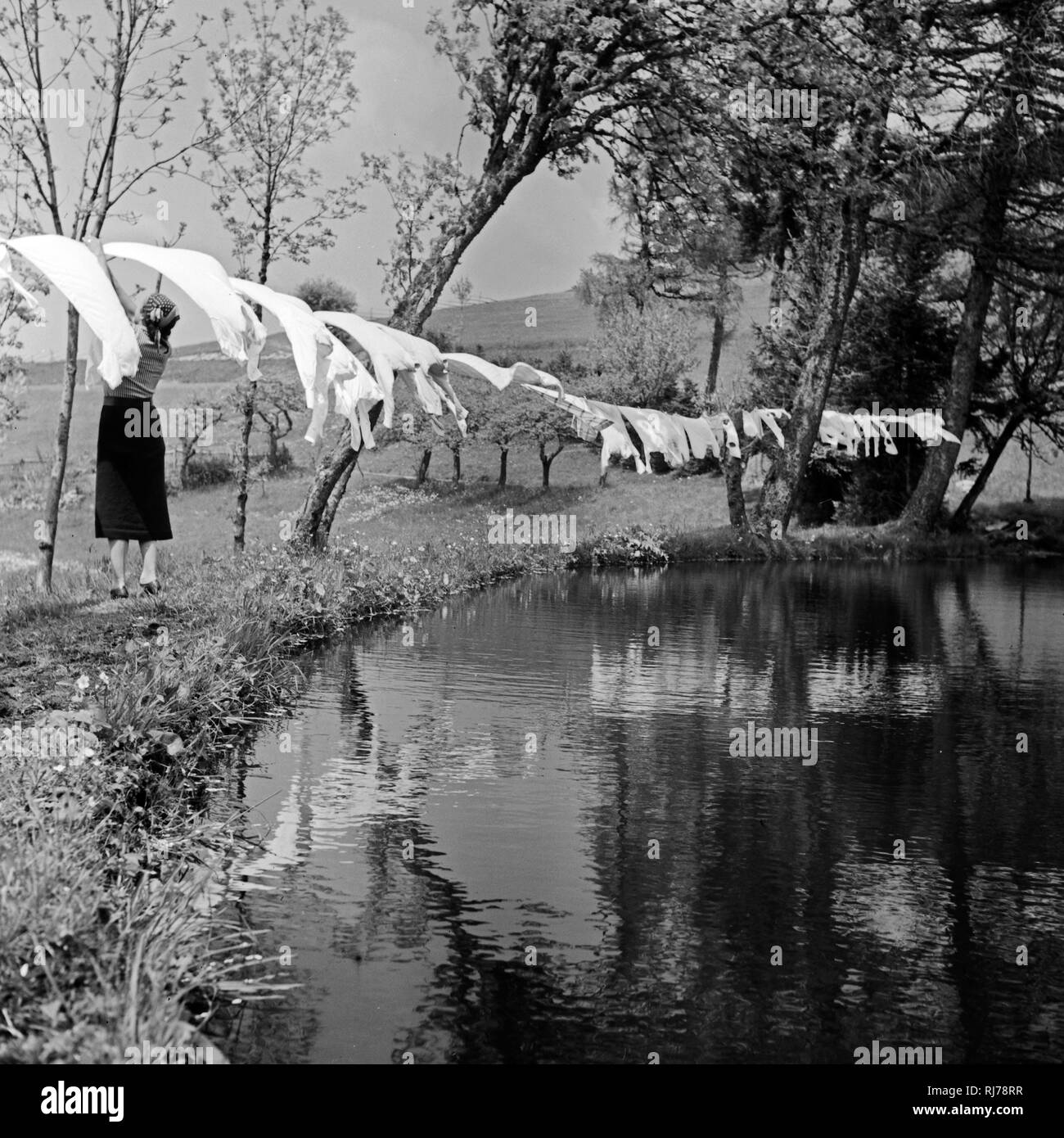 Eine Hausfrau hängt die frisch gewaschene Wäsche zum Trocknen auf die Leine im Schwarzwald, Deutschland 1930er Jahre Stock Photo