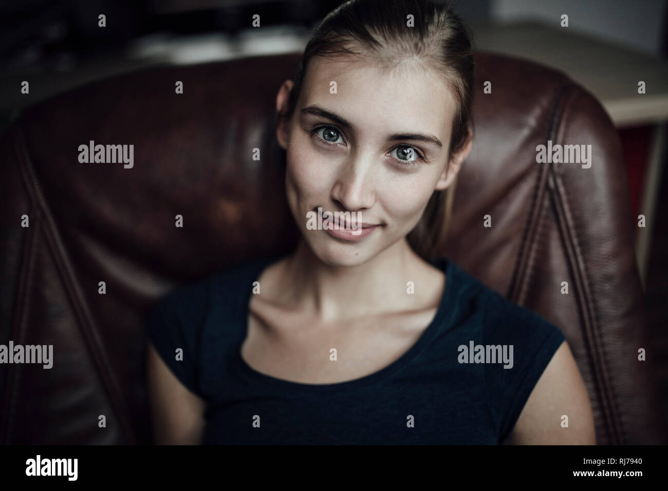 junge Frau sitzt in Sessel und blick in Kamera Stock Photo