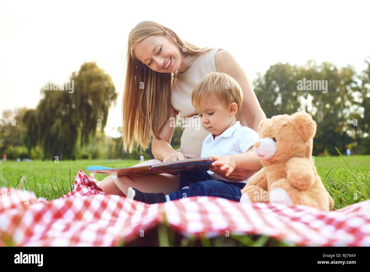 Mother with child reads on the grass in the park.  Stock Photo