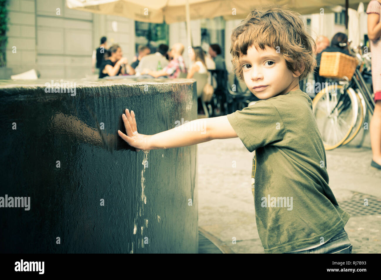 Child with green sweater in the center of Milan in the autumn Stock Photo