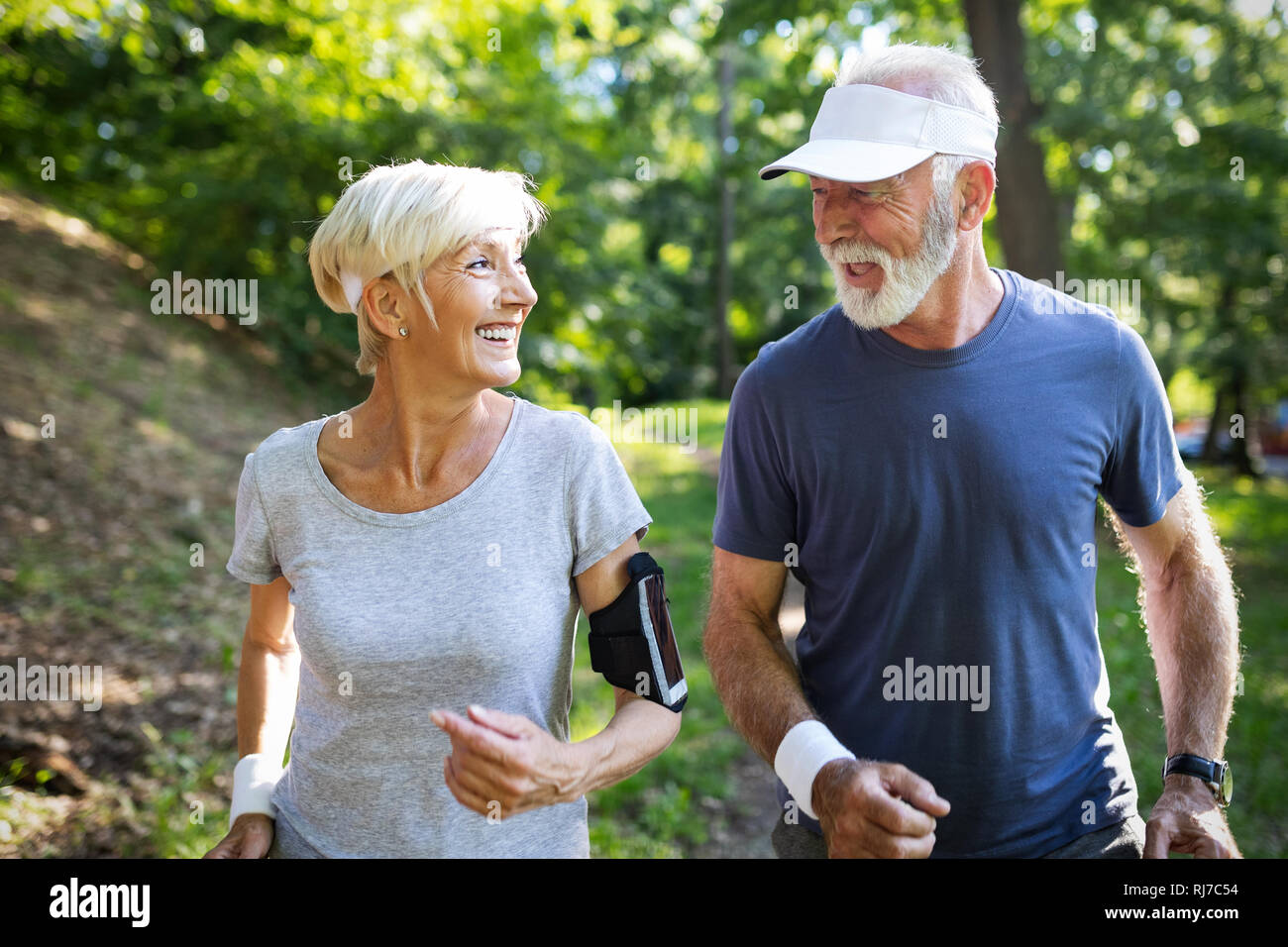 Healthy mature couple jogging in a park at early morning with sunrise Stock Photo