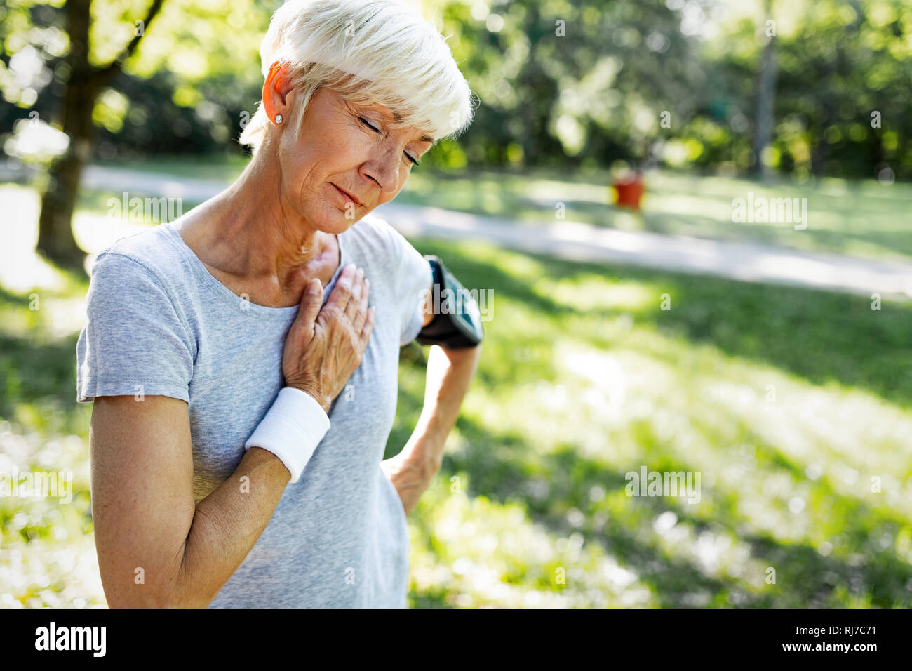 Senior woman with chest pain suffering from heart attack during jogging Stock Photo
