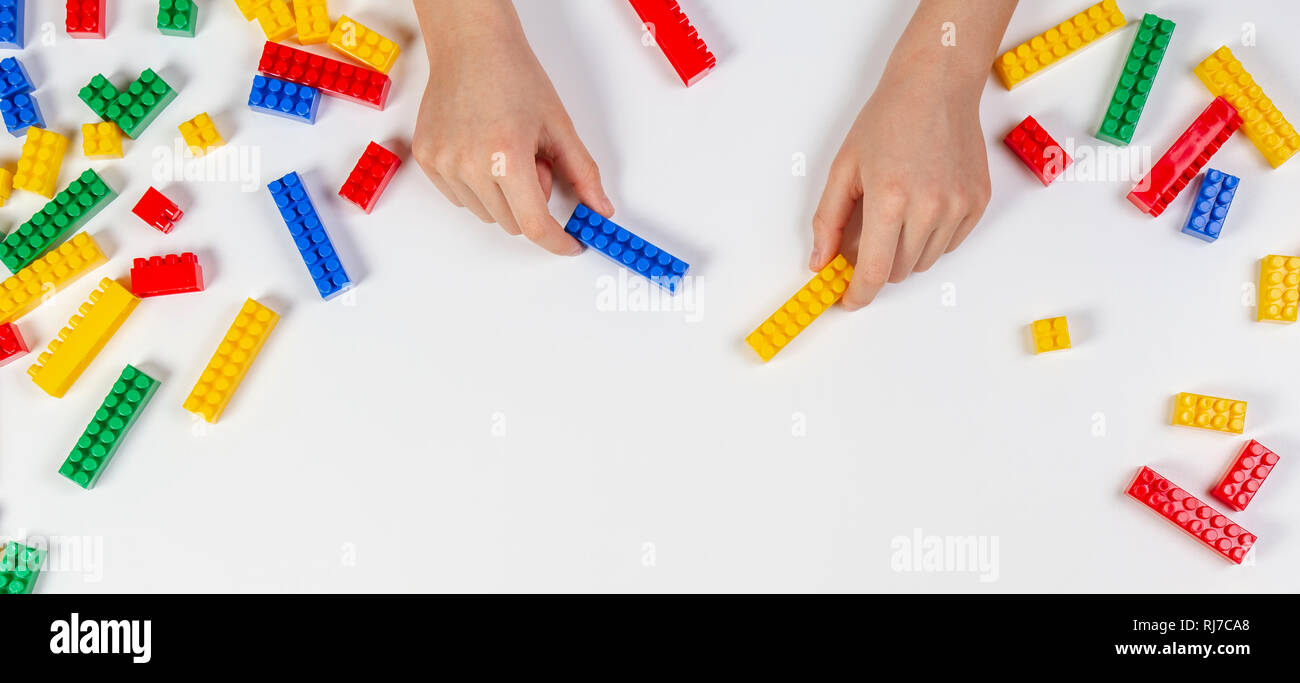 Kid hands playing with colorful building plastic bricks on white ...