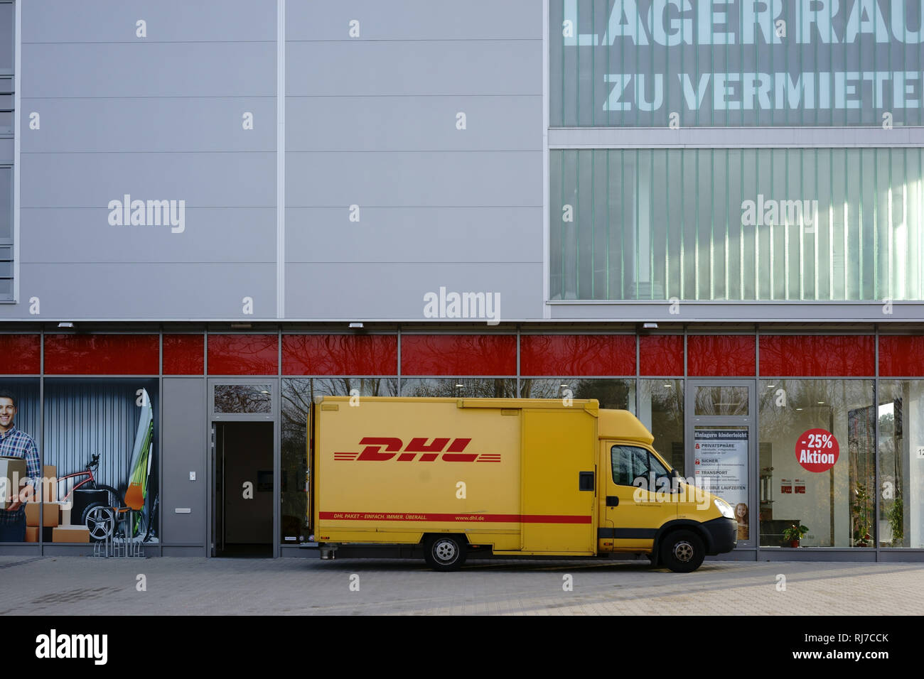 Ein Paketzusteller und Lieferfahrzeug von der DHL liefert Pakete aus. Stock Photo