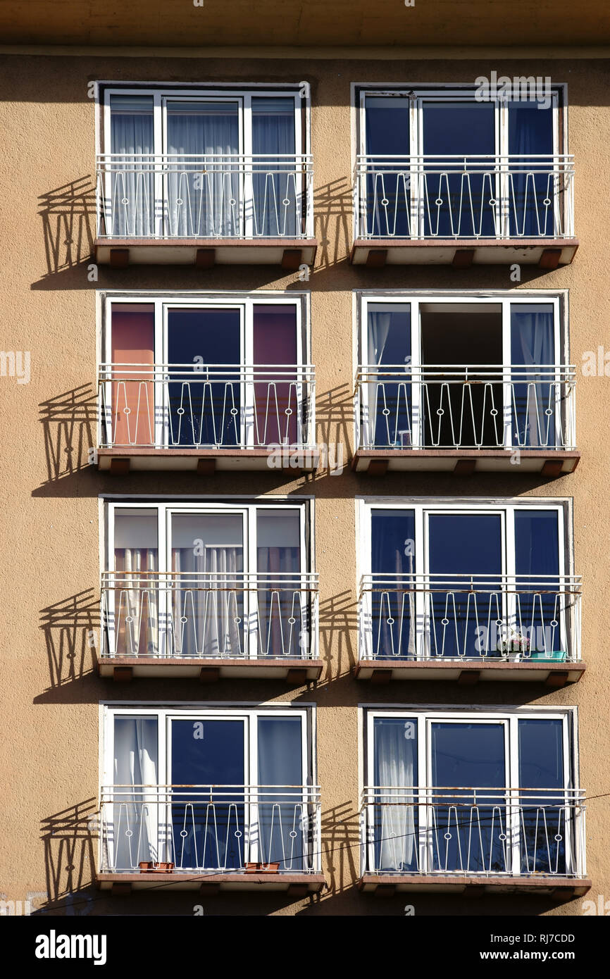 Die Geländer von kleinen Balkonen eines Mehrfamilienhauses werfen Schatten. Stock Photo