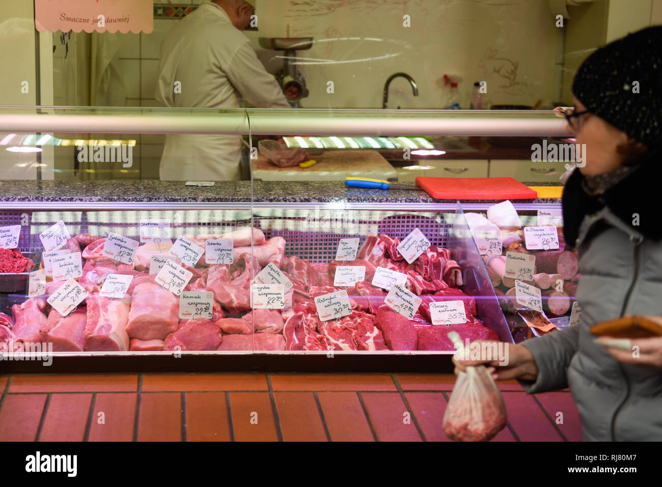 A woman seems buying pieces of meat at a meat market. European Union investigators began a weeklong visit to Poland on Monday after a video showing sick cows being illegally slaughtered during night at a slaughterhouse in the northeastern Polish town of Ostrow Mazowiecka . The meat from the abattoir went to Estonia, Finland, France, Hungary, Lithuania, Portugal, Romania, Spain, and Sweden. European Union investigators began a weeklong visit to Poland on Monday for inspections. Stock Photo