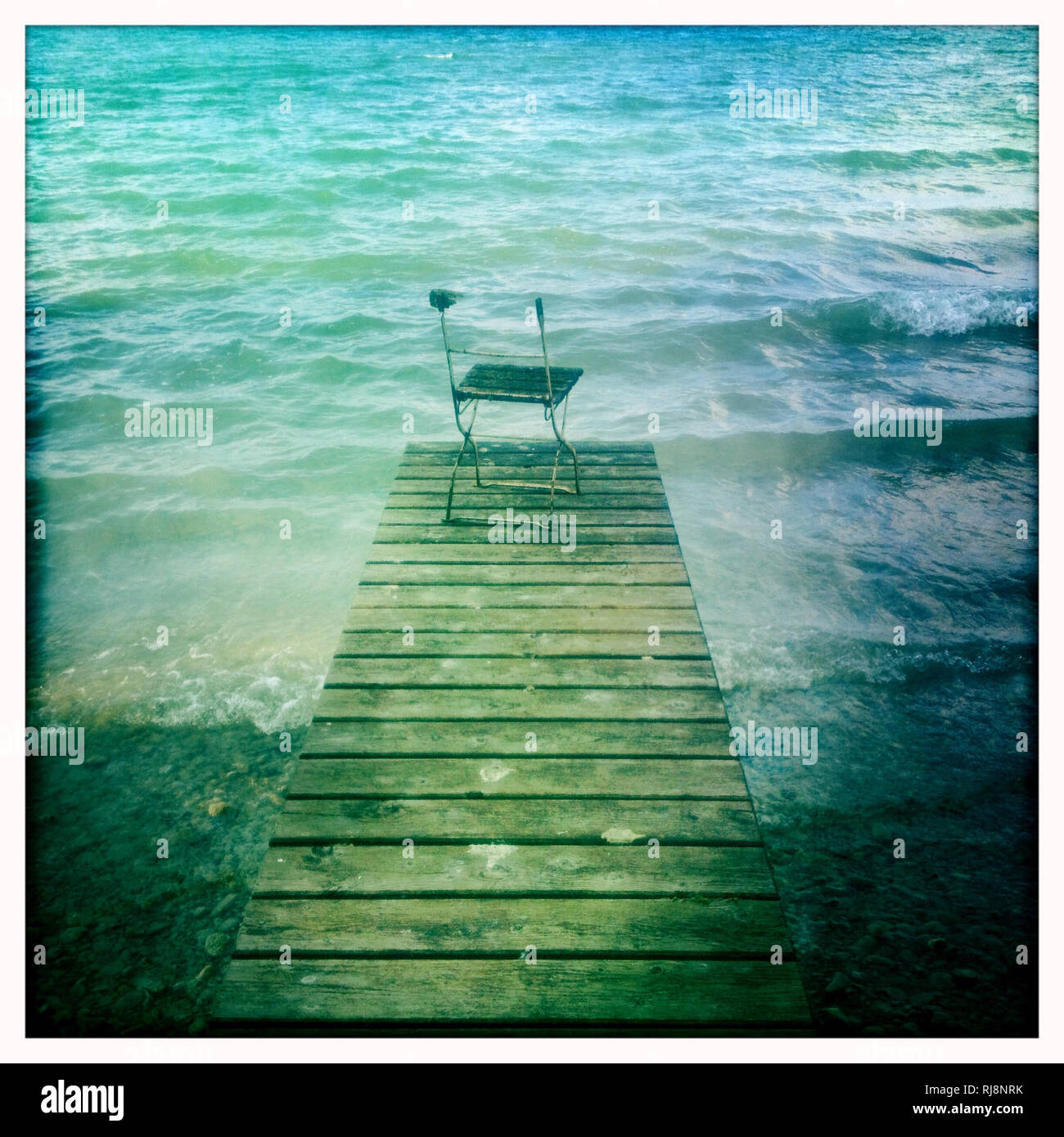 kaputter Stuhl auf einem Steg am See Stock Photo