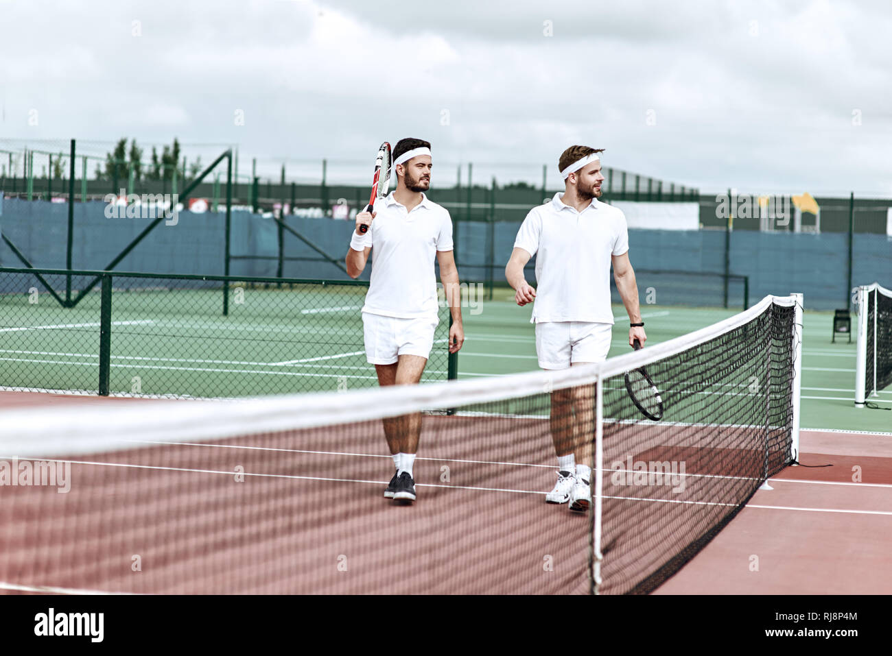 Two tennis players in white sportswear with rackets in their hands ...