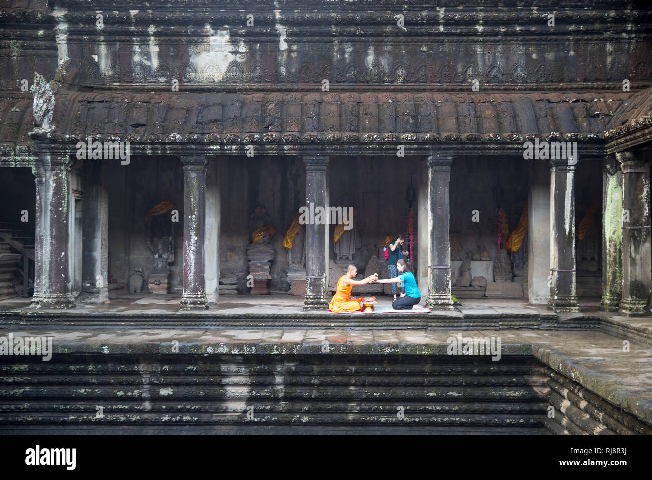 Siem Reap, Angkor, Angkor Wat Tempel, ein Mönch spricht für einen Dollar ein Gebet für eine Touristin Stock Photo