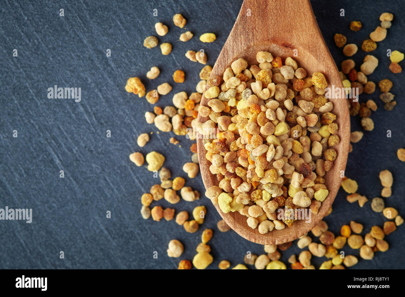 Bee pollen grains in wooden spoon. Top view with copy space Stock Photo