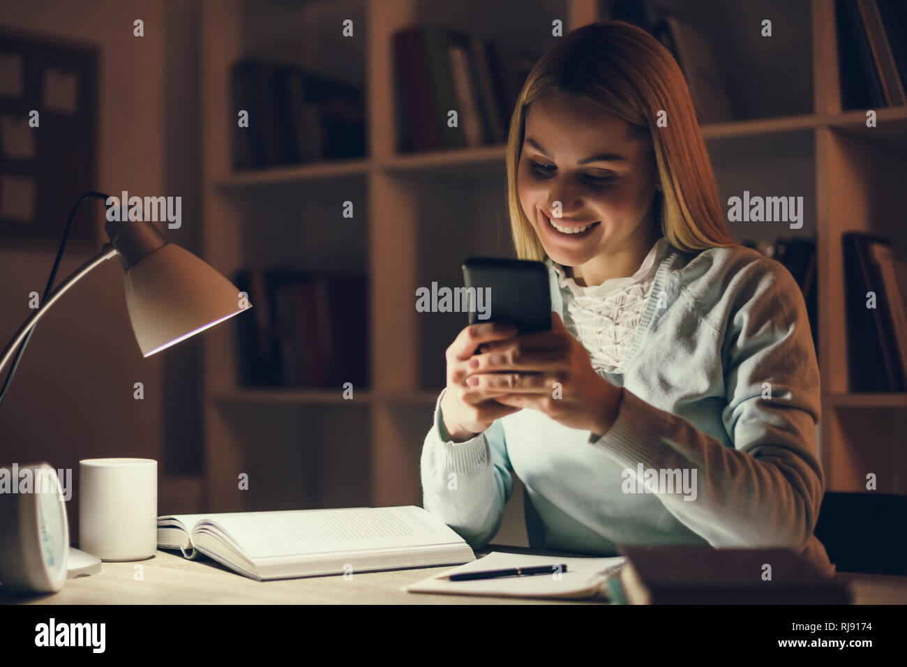 Student learning at home. Using smartphone. Stock Photo