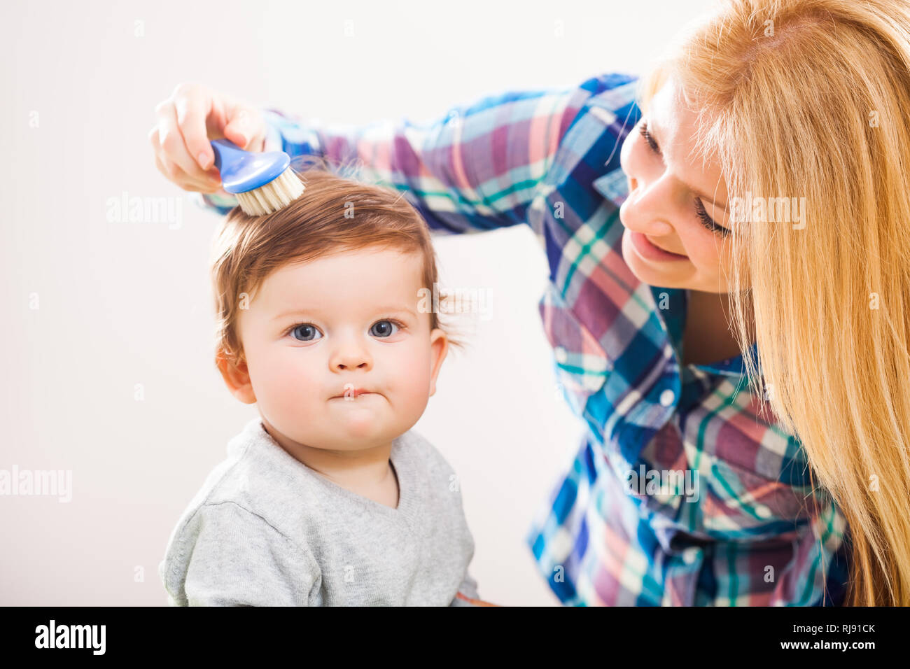 Mother brushing hair of her baby boy Stock Photo Alamy