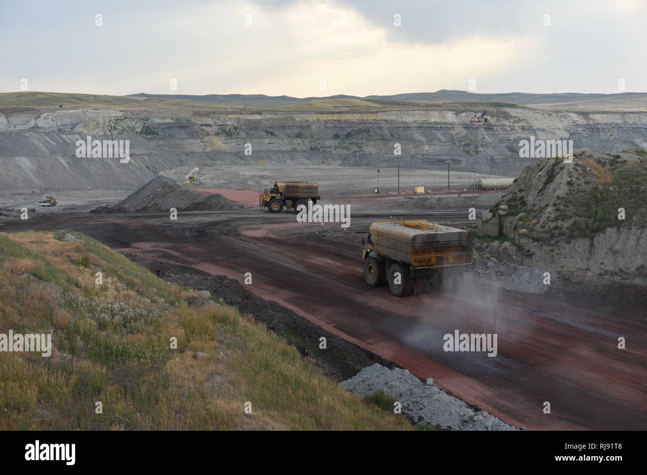 Large water trucks spray water on roads to control dust, open pit coal mining, Powder River Basin of Wyoming Stock Photo