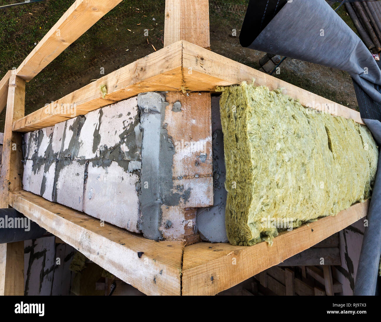 Roof construction and insulation with mineral wool. Wooden beams frame on walls of hollow foam insulation blocks. Roofing underlayment, water-resistan Stock Photo