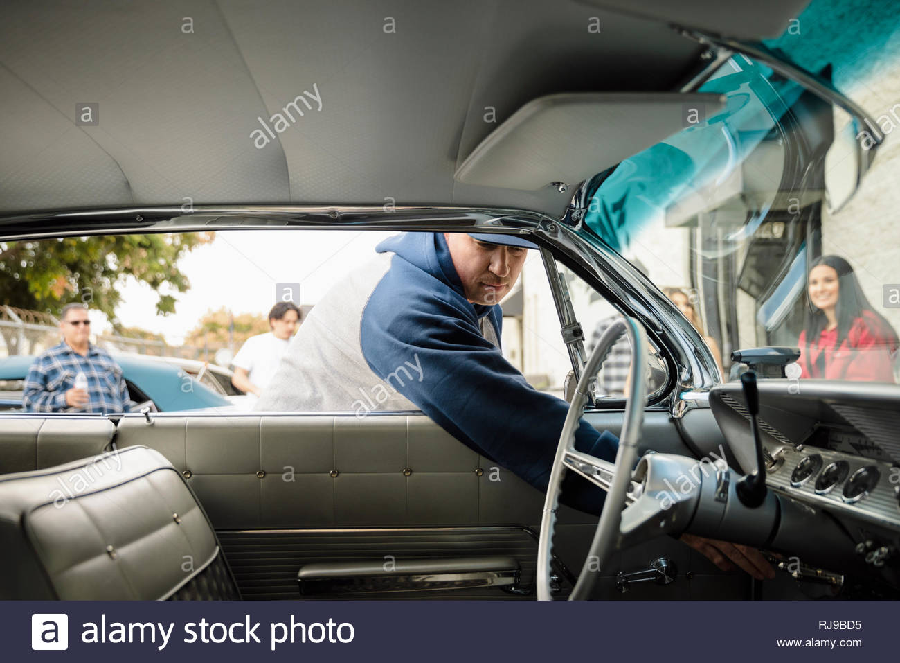 Latinx man reaching inside vintage car Stock Photo