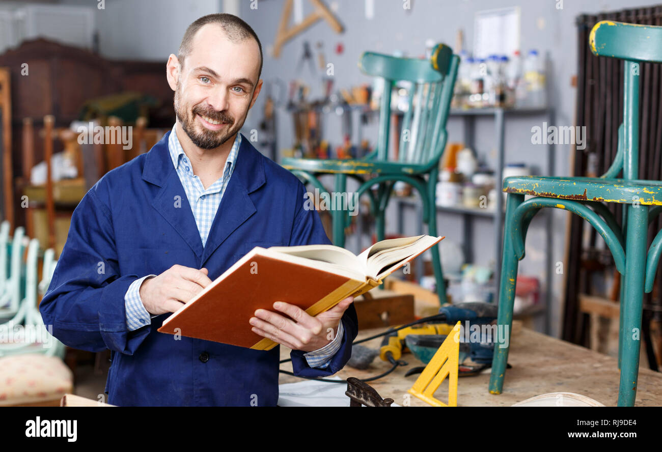 Craftsman looking at album in furniture restoration Stock