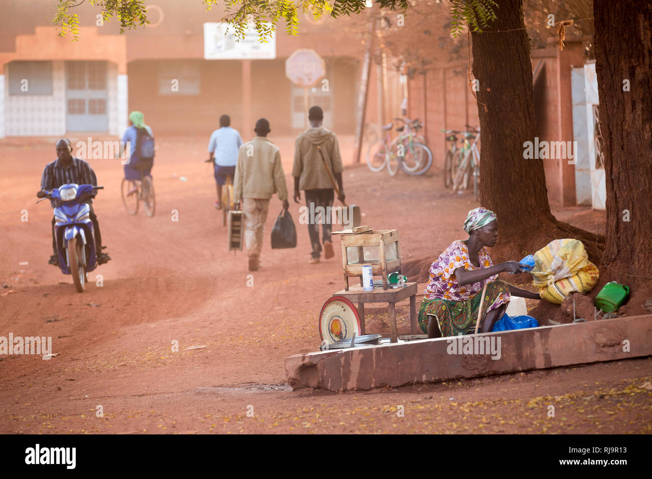 Yako, Burkina Faso, 29th November 2016; Street life outside the SEMUS compound as a woman prepares to make hot dumplings s street food in the early morning. Stock Photo