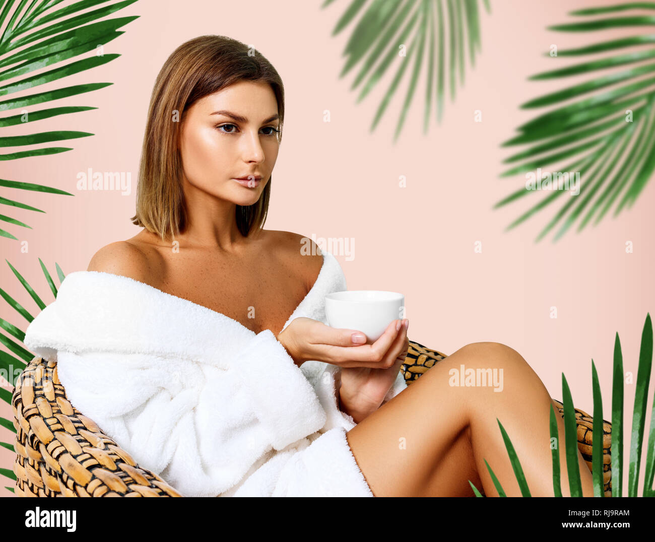 Woman in bathrobe drinking tea in spa salon. Stock Photo
