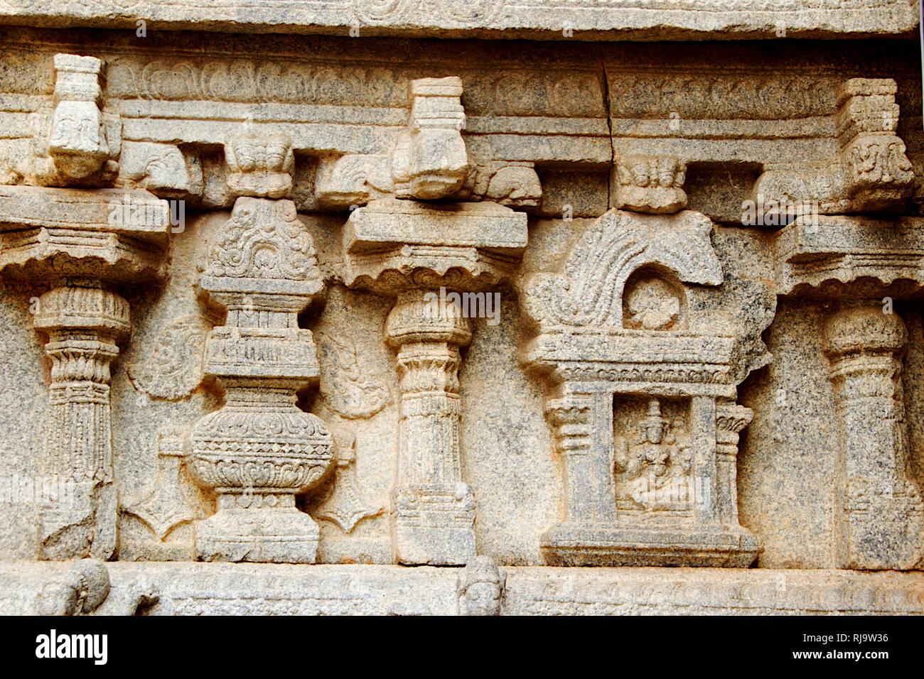 Decorative carving of pillars and deity on stone wall of
