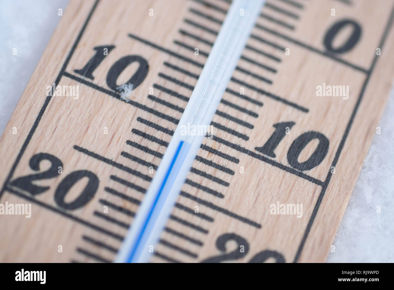 wooden thermometer in snow with freezing temperature macro Stock Photo