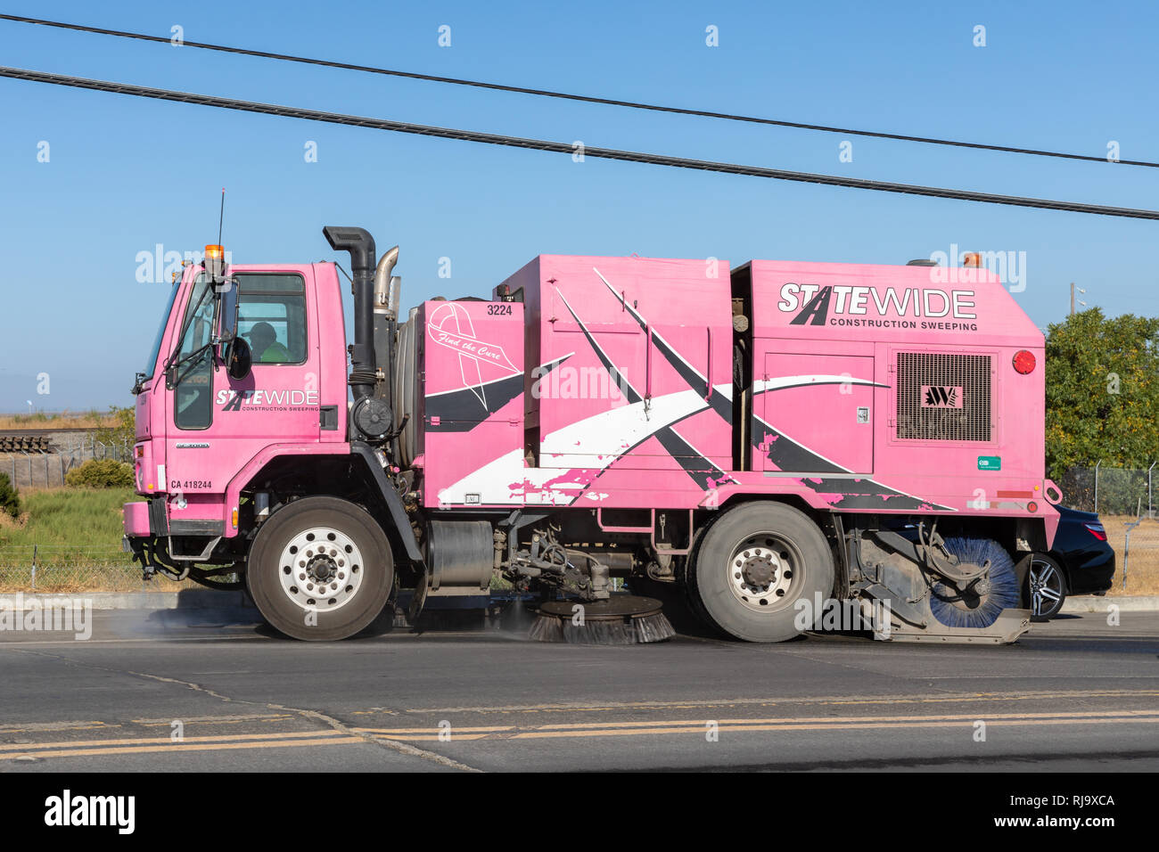 Pink street sweeper (Statewide Construction Sweeping) sweeping a road; Alviso, California, USA Stock Photo