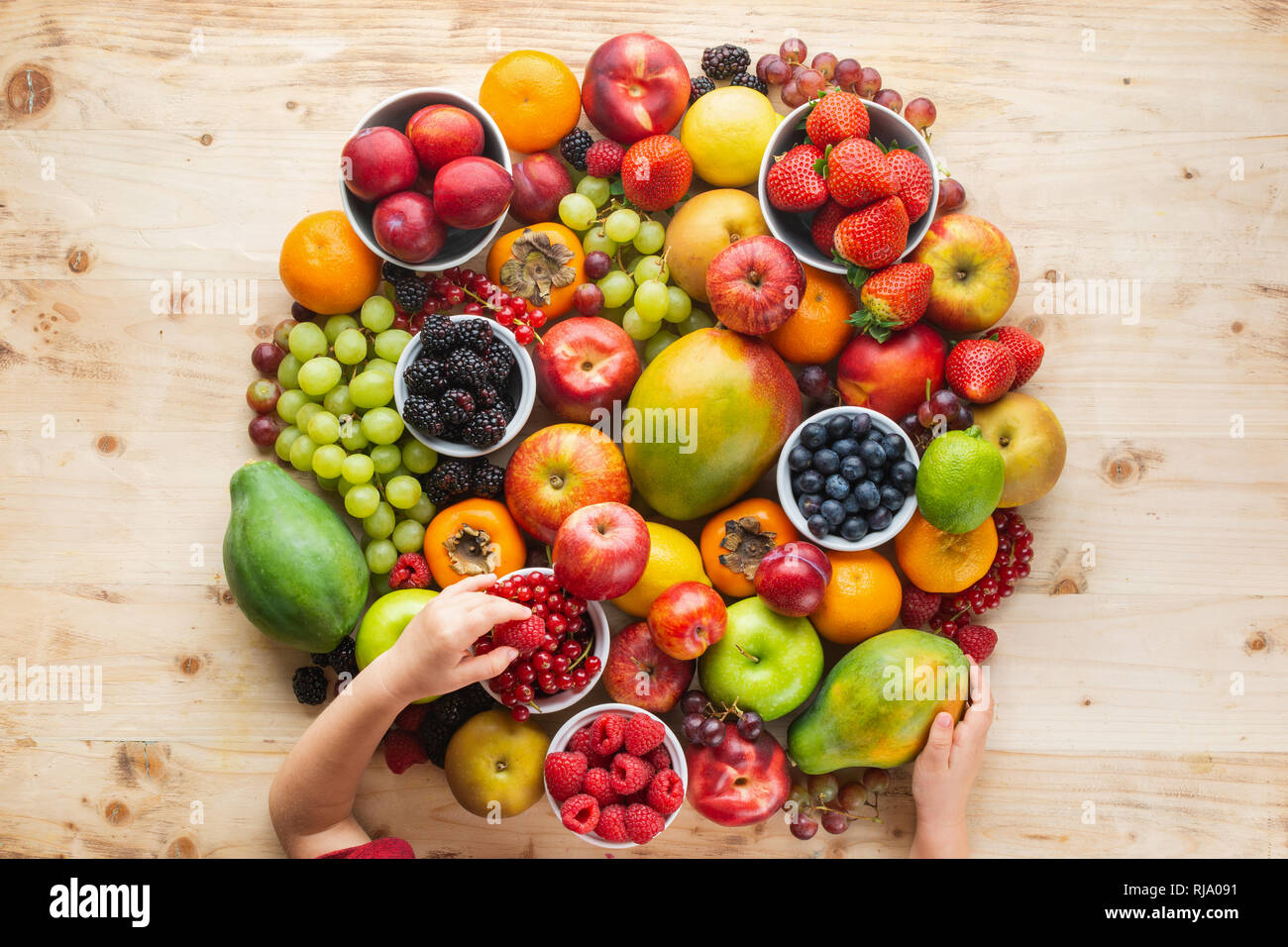 Child's hand holding circle make of rainbow fruits, strawberries ...