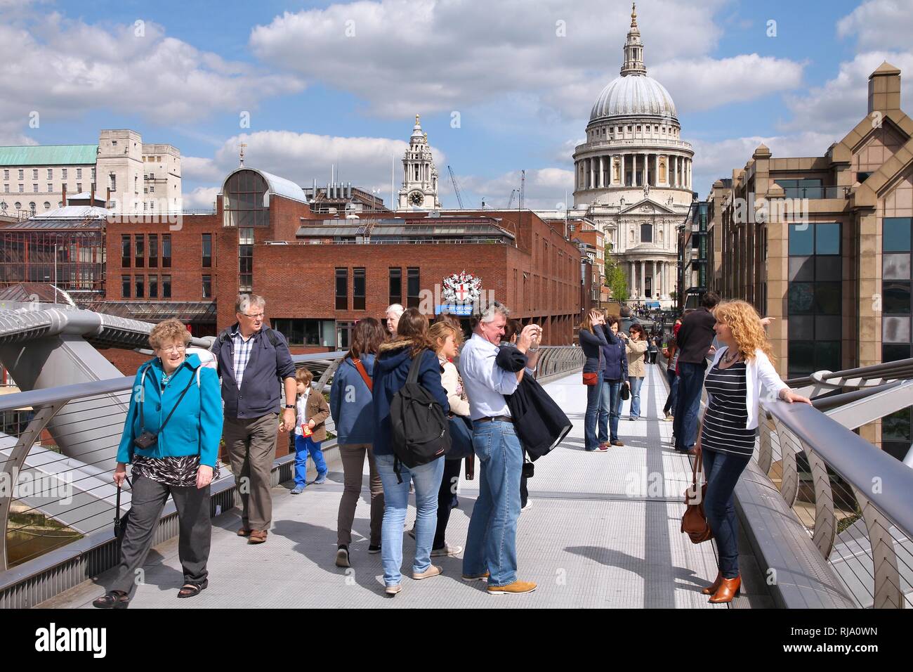 LONDON, UK - MAY 13, 2012: People walk the Millennium Bridge in London. With more than 14 million international arrivals in 2009, London is the most v Stock Photo