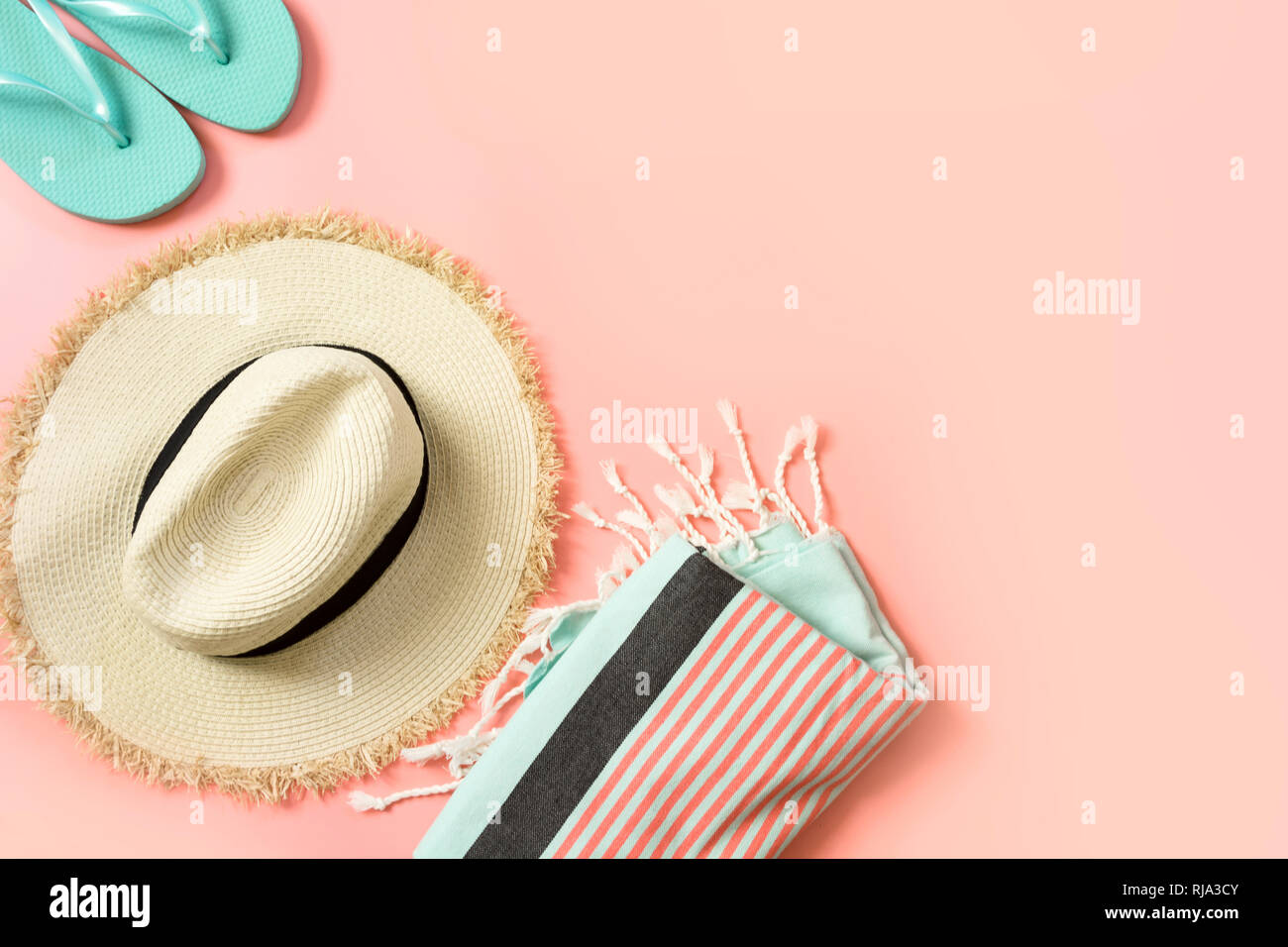 Female outfit for beach. Straw sunhat and beach slaps on punchy pink with space for text. Summer tropical concept. Stock Photo