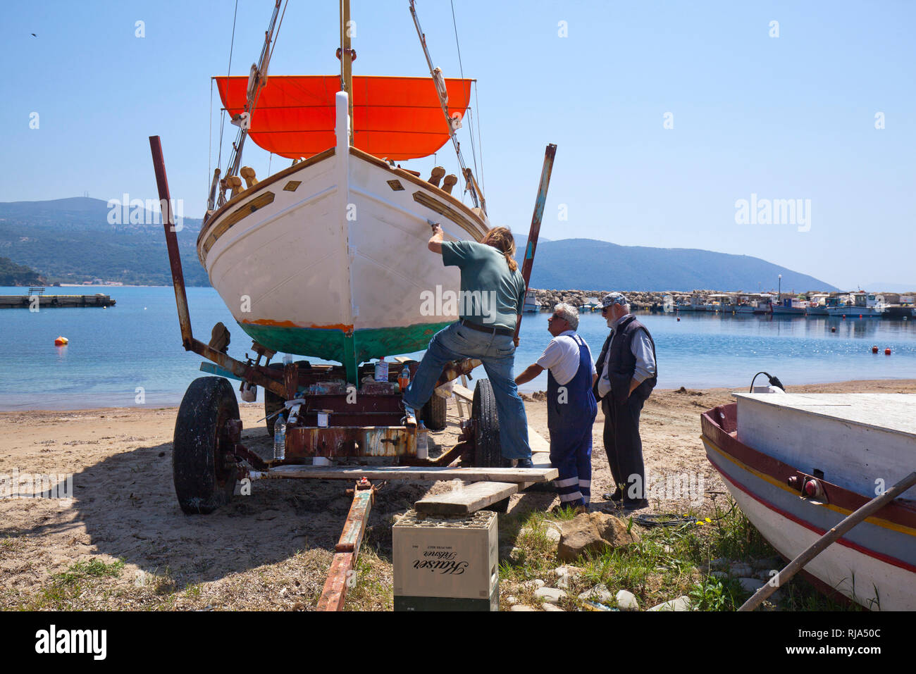 Men restore fishing boat at the harbor of Finikounda in Greece Stock Photo