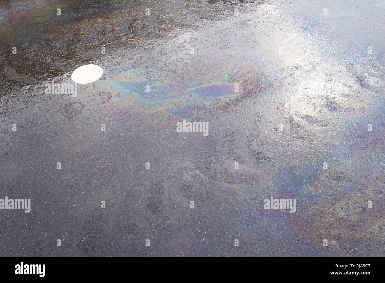rainbow streaks from spilled engine oil on a wet city road in Moscow