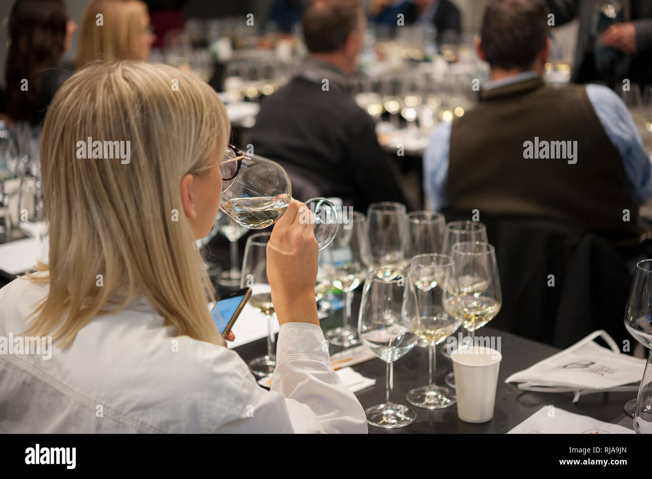 People tasting white wine during a masterclass. Blonde female in the foreground Stock Photo