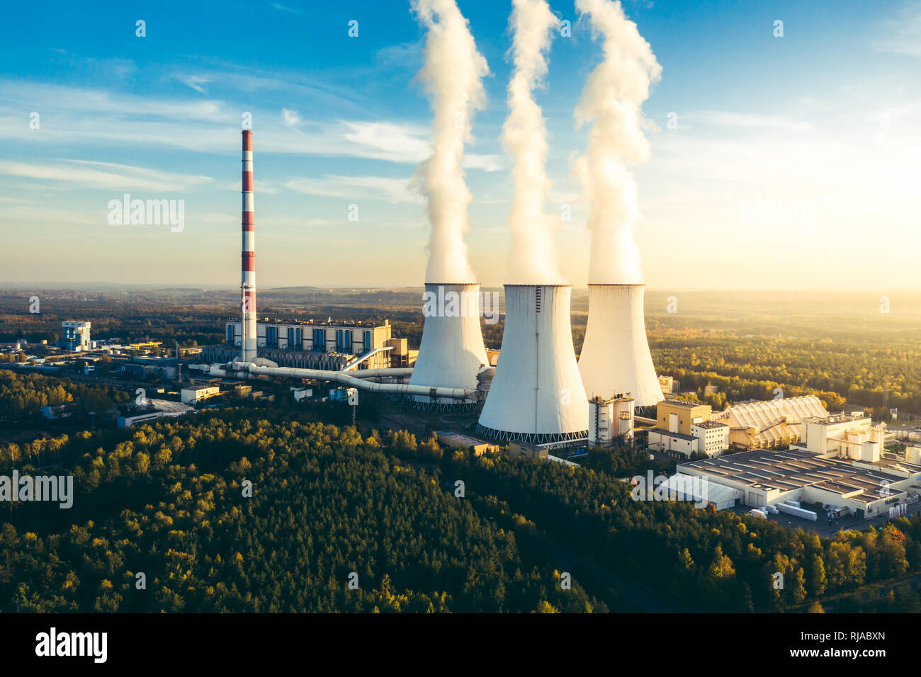 A Power plant with white smoke over it's chimneys Stock Photo