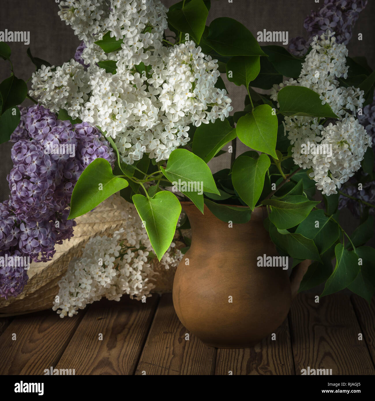Still-life with a bouquet of lilacs and a straw hat Stock Photo