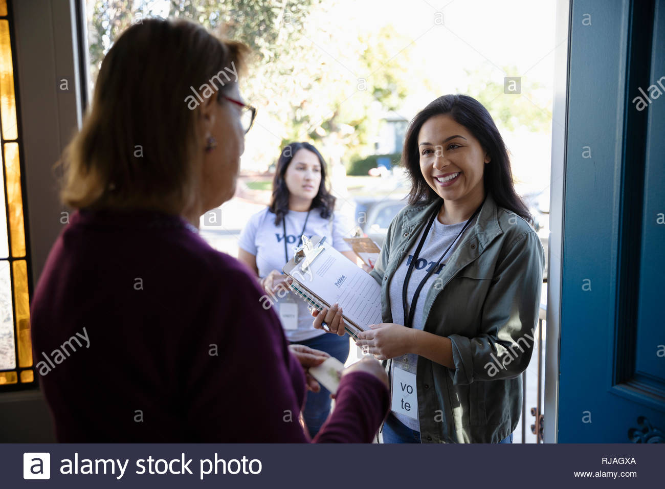 Latinx Female Volunteer Canvassing Voters Door To Door Stock