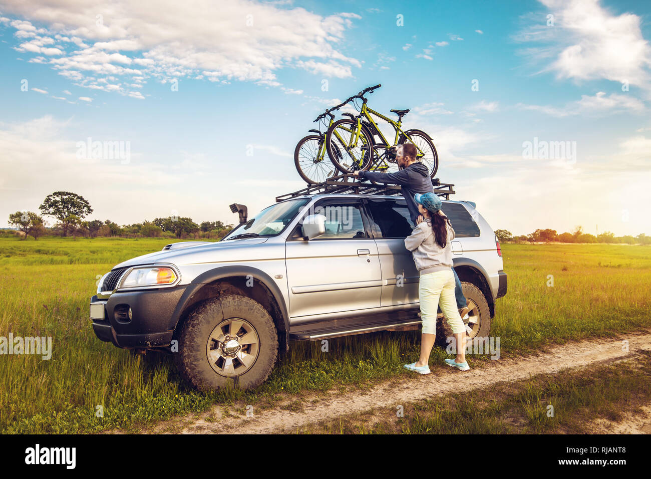 Couple taking off their bicycles from roof rack of the car Stock Photo