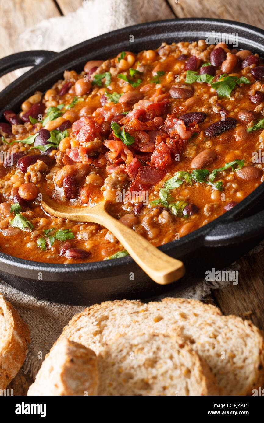 American cowboy beans with ground beef, bacon in a spicy sauce close-up on the table. vertical Stock Photo