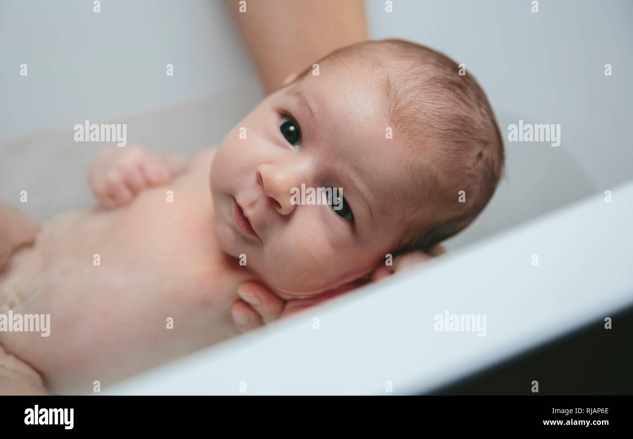 Newborn in the bathtub held by her mother Stock Photo Alamy
