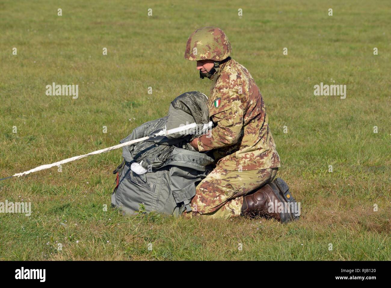 Italian Army paratrooper, Command Sgt. Maj. Simoni Roncari, recovers his T-11 parachute after conducting airborne operations onto Juliet Drop Zone in Pordenone in Italy, Nov. 3, 2016. Stock Photo