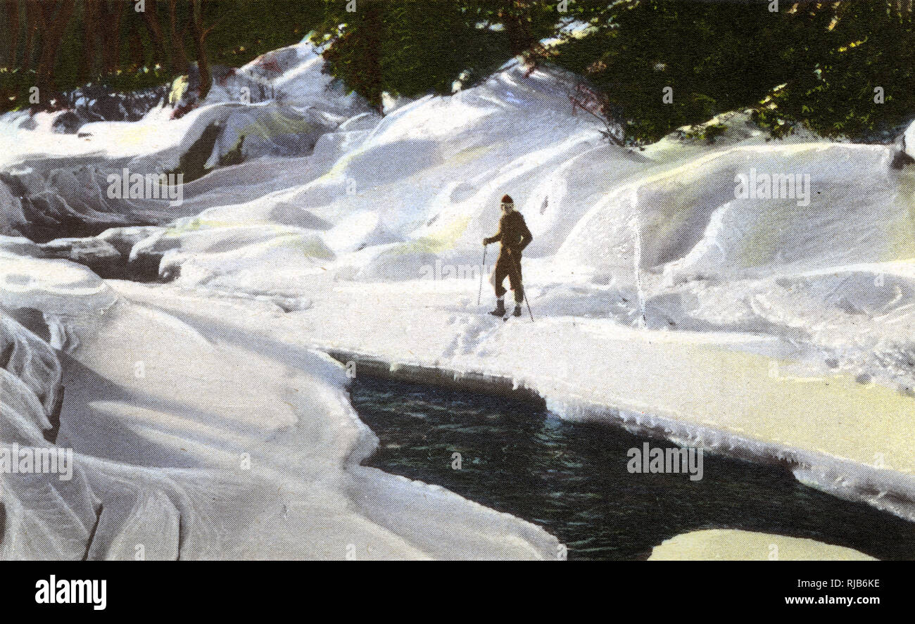 Lake Placid, N.Y., USA - Skier pauses by Winter Brook Stock Photo
