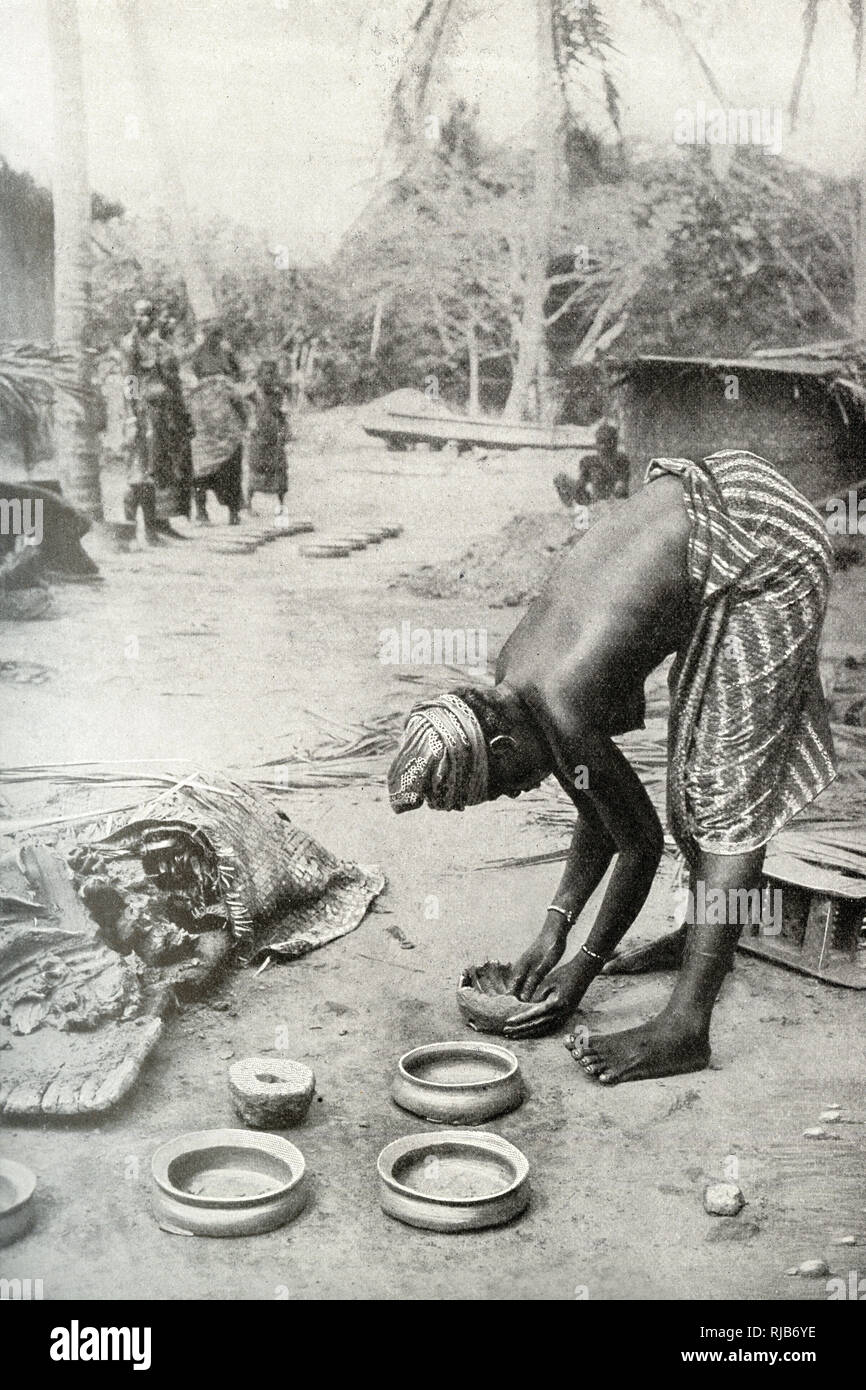 Woman of the Gold Coast (then part of the British Empire), West Africa, shaping clay around a stone mould to make pottery. Stock Photo
