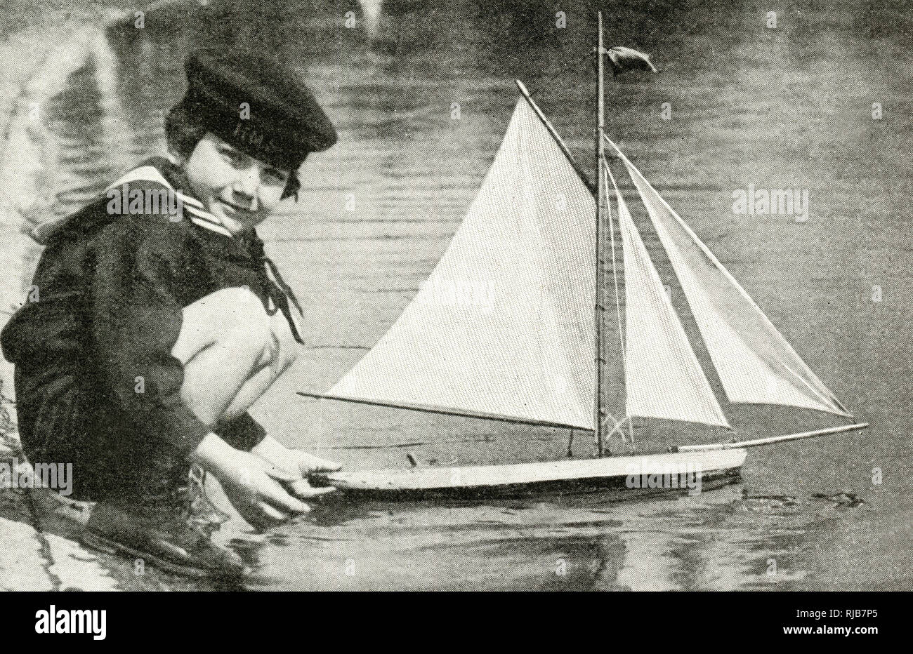 Boy in a sailor suit with his model boat at the Round Pond, Kensington Gardens, London. Stock Photo