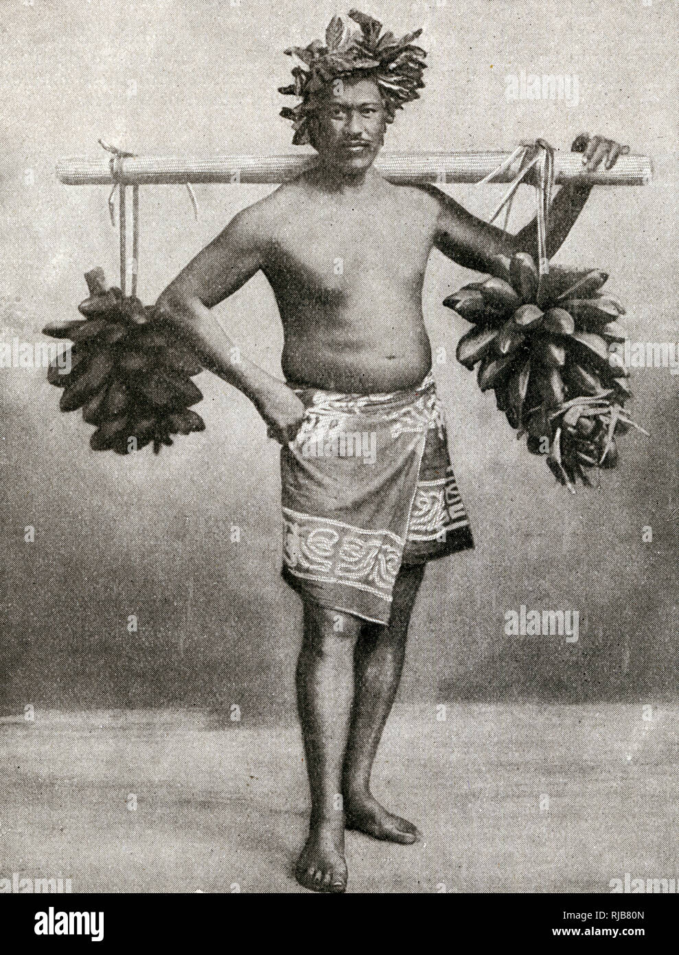 Man carrying fruit on a pole, Tahiti, French Polynesia. Stock Photo