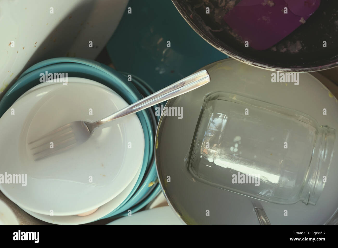 A Messy Pile of Dirty Dishes And Utensils In Kitchen Sink Stock Photo