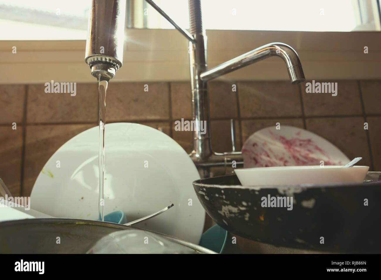 A Messy Pile of Dirty Dishes And Utensils In Kitchen Sink Stock Photo